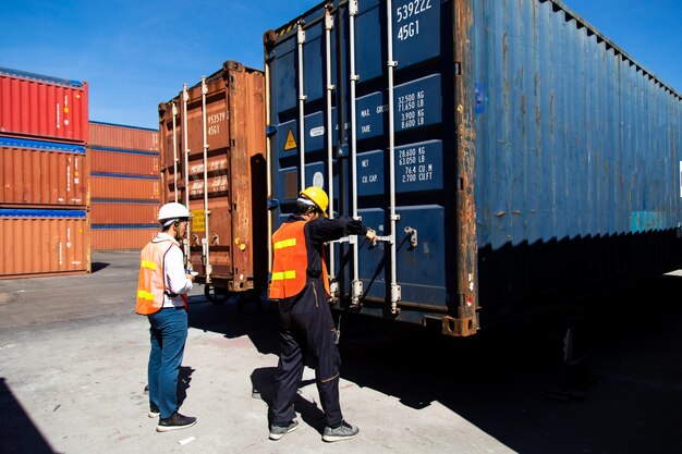 Concetto di assicurazione marittima e vettore. Due uomini del porto che lavorano al cantiere di container. Casella di contenitori di caricamento di controllo del caposquadra al porto di spedizione. Logistica aziendale Importazione ed esportazione del concetto.