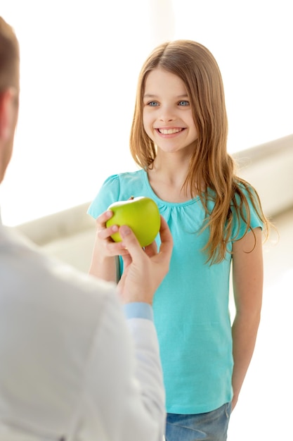 concetto di assistenza sanitaria, bambino e medicina - medico maschio che dà una mela alla bambina sorridente