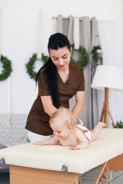 Concetto di assistenza sanitaria e medica. Bambino felice che ha massaggio con massaggiatrice femmina professionale.