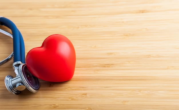 Concetto di assistenza sanitaria e medica. Stetoscopio e cuore rosso sul tavolo di legno.