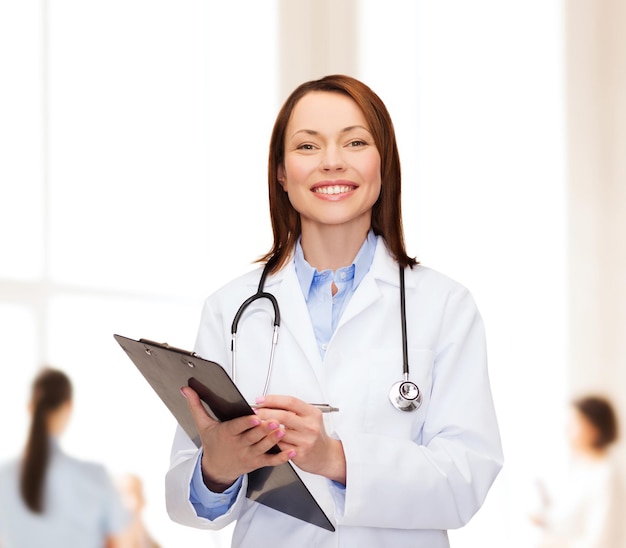concetto di assistenza sanitaria e medicina - dottoressa sorridente con appunti e stetoscopio