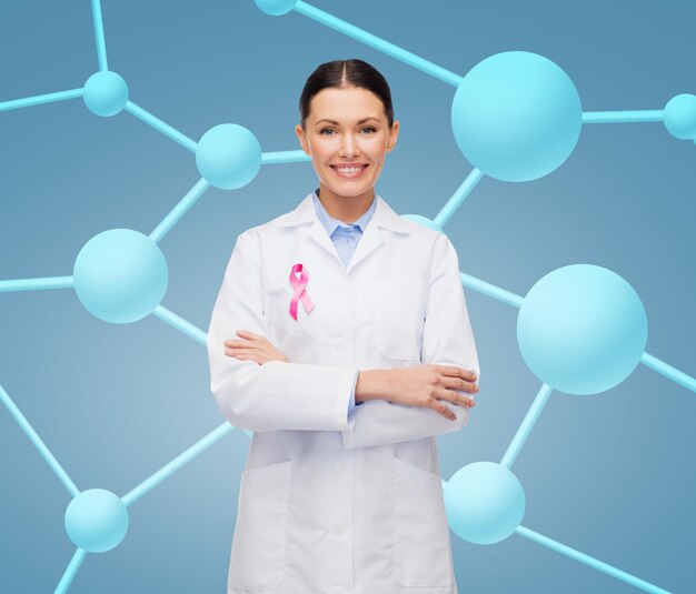 concetto di assistenza sanitaria e medicina - dottoressa sorridente con nastro rosa per la consapevolezza del cancro su sfondo molecolare