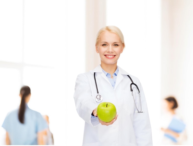 concetto di assistenza sanitaria e medicina - dottoressa sorridente con stetoscopio e mela verde