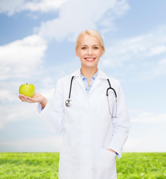 concetto di assistenza sanitaria e medicina - dottoressa sorridente con stetoscopio e mela verde