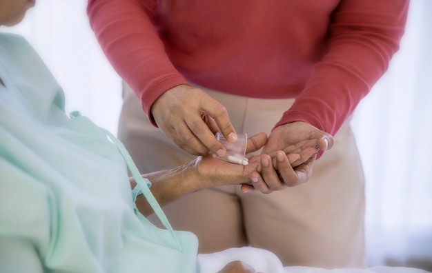 Concetto di assistenza sanitaria; Figlia che si prende cura della madre anziana in ospedale, dà a sua madre la medicina