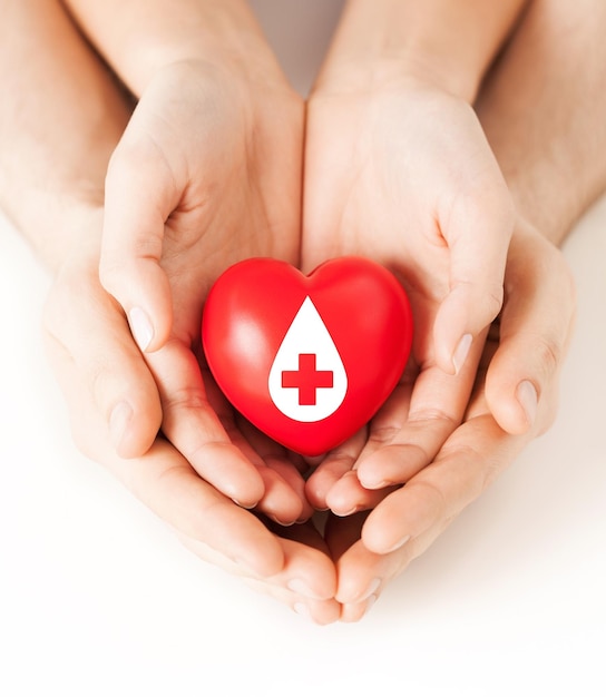 concetto di assistenza sanitaria, medicina e donazione di sangue - mani maschili e femminili che tengono il cuore rosso con il segno del donatore