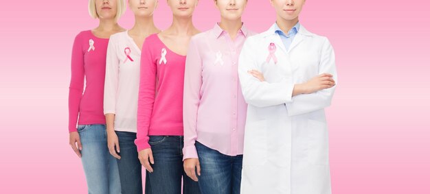 concetto di assistenza sanitaria, persone e medicina - primo piano di donne in camicie bianche con nastri di consapevolezza del cancro al seno su sfondo rosa