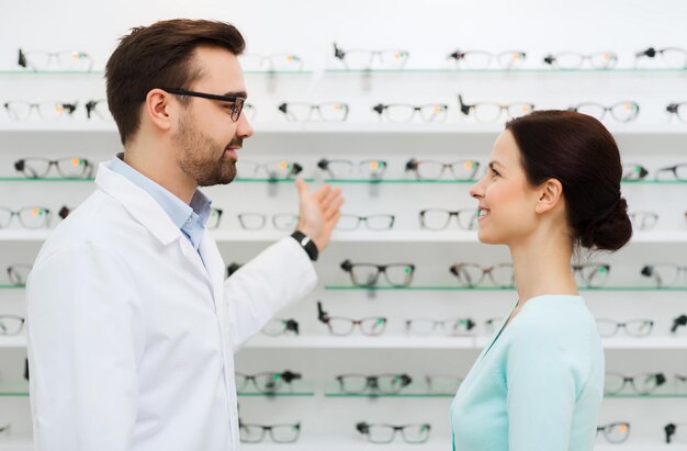 concetto di assistenza sanitaria, persone, vista e visione - ottico che mostra gli occhiali alla donna al negozio di ottica