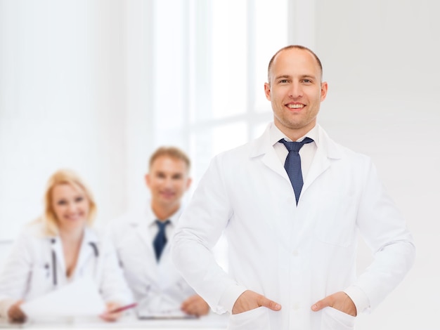 concetto di assistenza sanitaria, professione, lavoro di squadra e medicina - medico maschio sorridente in camice bianco su un gruppo di medici