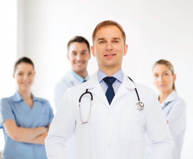 concetto di assistenza sanitaria, professione, lavoro di squadra, persone e medicina - medico maschio sorridente con stetoscopio in camice bianco su un gruppo di medici