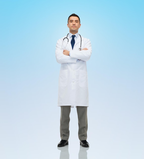 concetto di assistenza sanitaria, professione, persone e medicina - medico maschio in stetoscopio camice bianco su sfondo blu