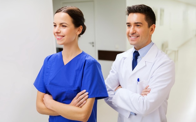 concetto di assistenza sanitaria, professione, persone e medicina - medico sorridente in camice bianco e infermiere in ospedale