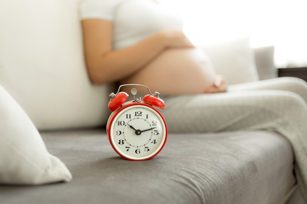 Concetto di attesa per il bambino. Sveglia contro la donna incinta