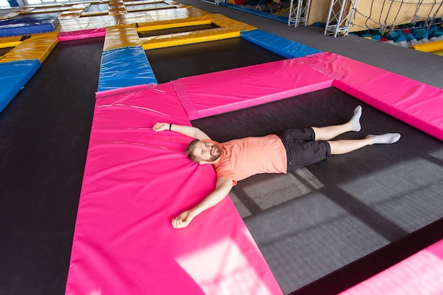 Concetto di attività di fitness, divertimento, tempo libero e sport - uomo disteso su un trampolino al chiuso, vista dall'alto