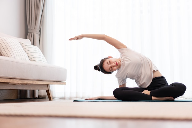 Concetto di attività produttiva una giovane donna adulta che indossa una t-shirt bianca che pratica la flessibilità del suo corpo facendo pilates mat.