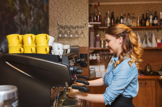 concetto di attrezzatura, caffetteria, persone e tecnologia - donna barista che fa il caffè con la macchina per caffè espresso al bar caffetteria o nella cucina del ristorante