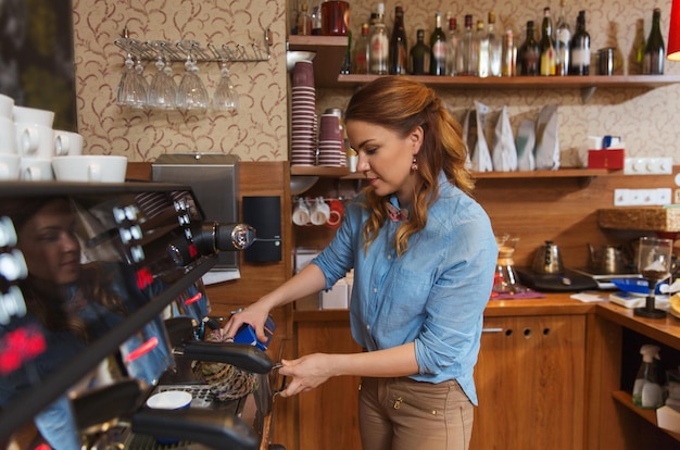 concetto di attrezzatura, caffetteria, persone e tecnologia - donna barista che versa la panna nella brocca alla macchina del caffè