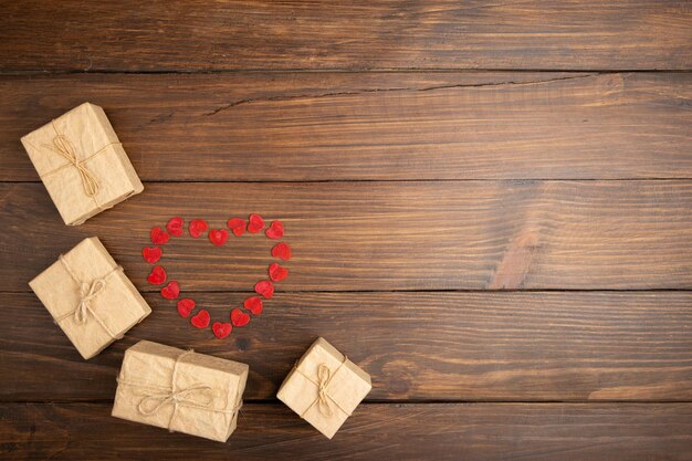 Concetto di auguri di San Valentino Piccoli cuori rossi in legno e scatole regalo sullo sfondo di legno Biglietto di auguri di San Valentino