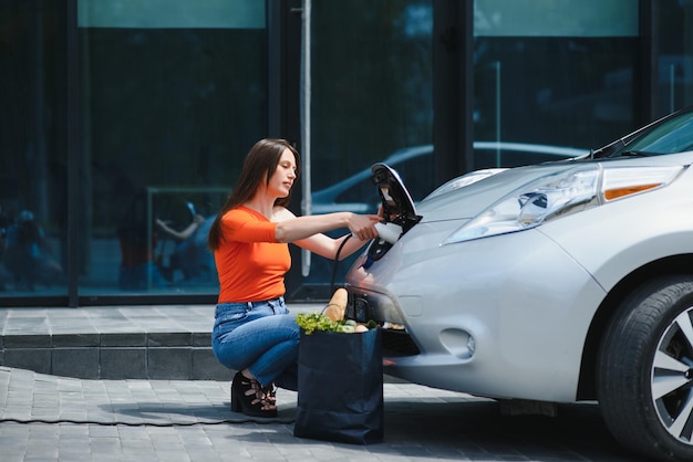 Concetto di auto elettrica ecologica Donna in attesa di ricarica dell'auto elettrica