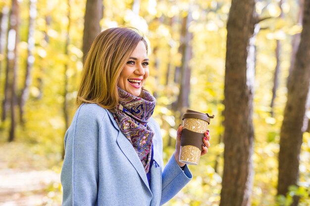 Concetto di autunno, bevande e persone - Donna che tiene tazza di bevanda calda