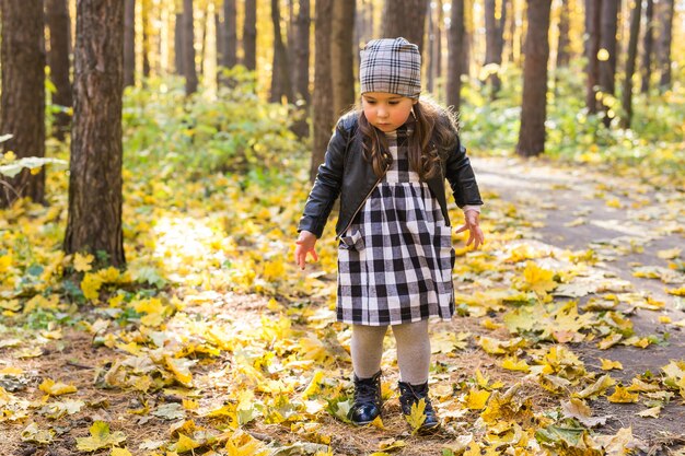 Concetto di autunno, infanzia e stagione - Bambina che gioca nel parco in autunno