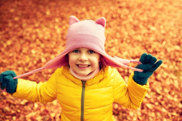 concetto di autunno, infanzia, natura e persone - bambina felice sopra le foglie cadute nel parco