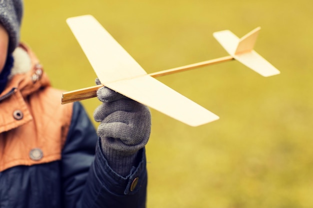 concetto di autunno, infanzia, sogno, tempo libero e persone - primo piano dell'aereo giocattolo che tiene la mano del ragazzino all'aperto