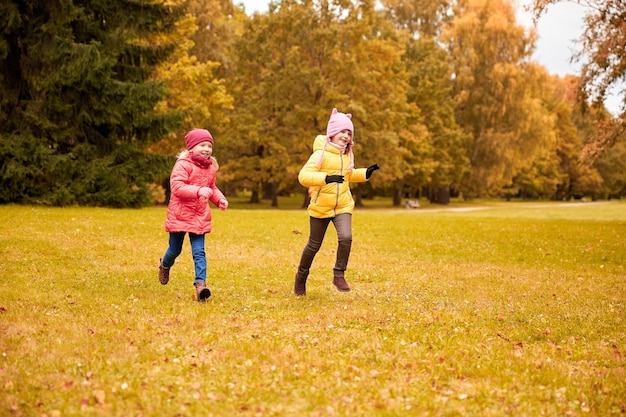 concetto di autunno, infanzia, tempo libero e persone - bambine felici che giocano a tag game e corrono nel parco all'aperto
