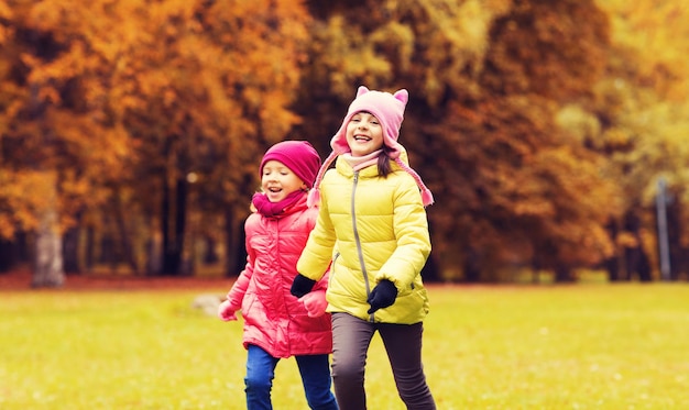 concetto di autunno, infanzia, tempo libero e persone - bambine felici che giocano a tag game e corrono nel parco all'aperto