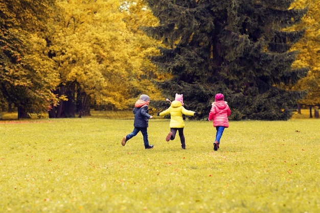 concetto di autunno, infanzia, tempo libero e persone - gruppo di bambini felici che giocano a tag game e corrono nel parco all'aperto