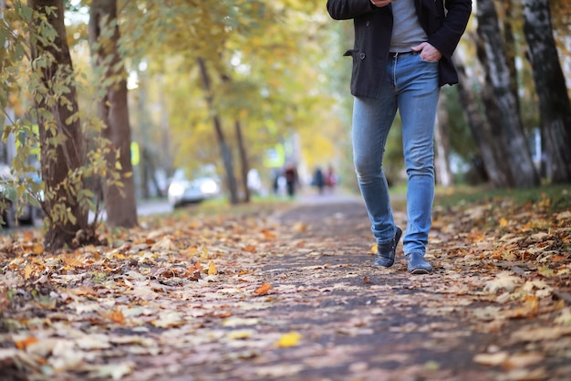 Concetto di autunno. Piedi dei pedoni sulla strada. Foglie d'autunno sul sentiero.