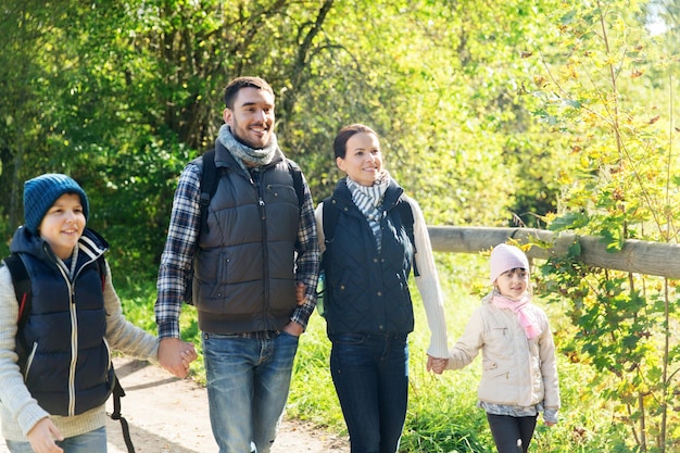 concetto di avventura, viaggio, turismo, escursione e persone - famiglia felice che cammina con gli zaini nei boschi