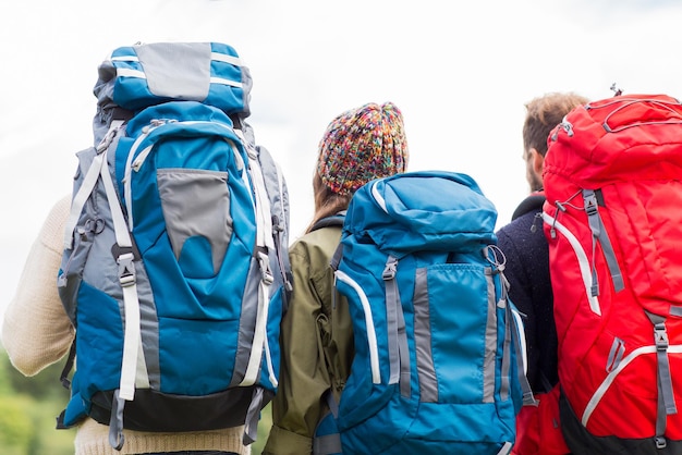 concetto di avventura, viaggio, turismo, escursione e persone - gruppo di amici che camminano con gli zaini dal retro