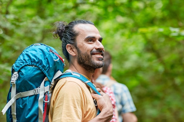 concetto di avventura, viaggio, turismo, escursione e persone - gruppo di amici sorridenti che camminano con gli zaini nei boschi