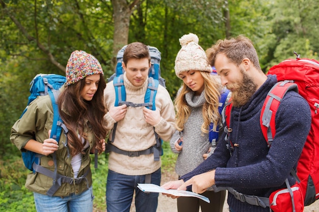 concetto di avventura, viaggio, turismo, escursione e persone - gruppo di amici sorridenti con zaini e mappa all'aperto