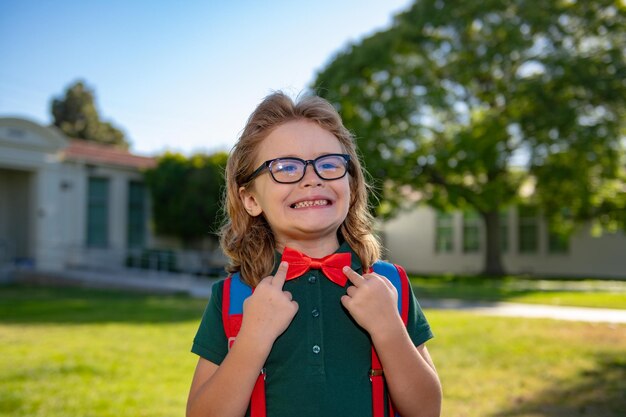 Concetto di bambino della scuola Simpatico allievo stupito in uniforme scolastica con zaino all'aperto Ritratto di scolaro nerd