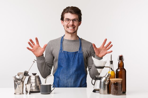 Concetto di barista, lavoratore barista e barista. Ritratto del giovane infastidito incazzato in grembiule che rende il caffè aggressivo e irritato con clienti maleducati,