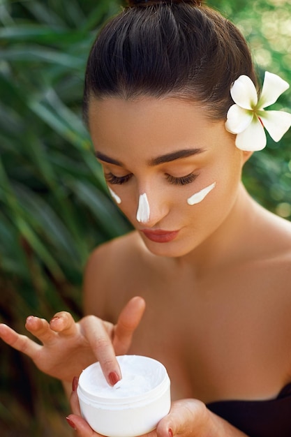 Concetto di bellezza e spa per la cura della pelle del viso Ritratto di una crema idratante femminile che tiene in mano