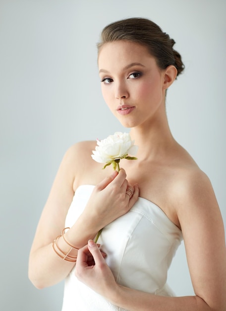 concetto di bellezza, gioielli, persone e lusso - bella donna asiatica o sposa in abito bianco con fiore di peonia, anello d'oro e bracciale