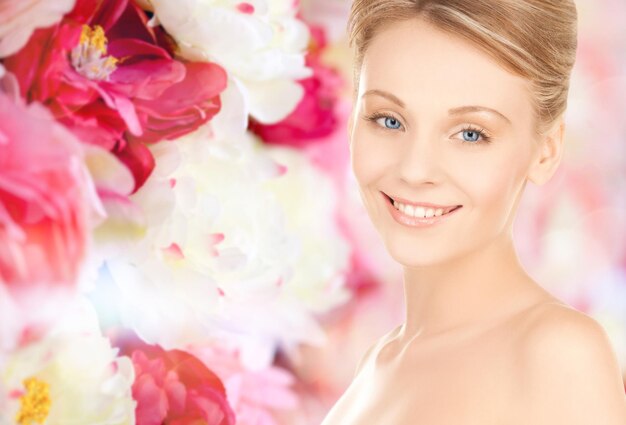 concetto di bellezza, persone e salute - bella giovane donna faccia su sfondo floreale rosa