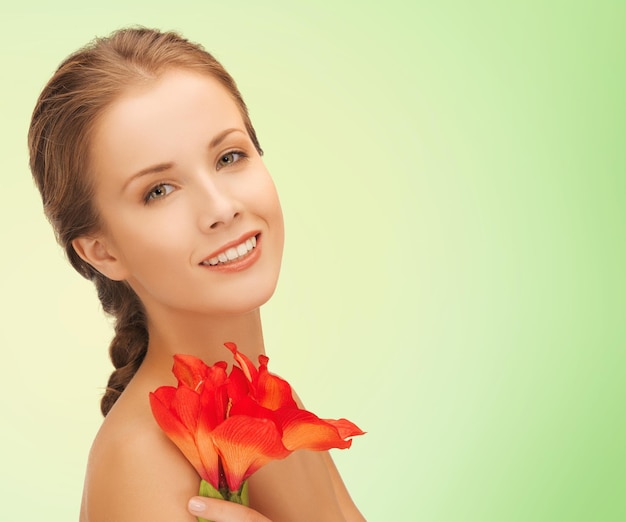 concetto di bellezza, persone e salute - bella giovane donna sorridente con fiori e spalle nude su sfondo verde