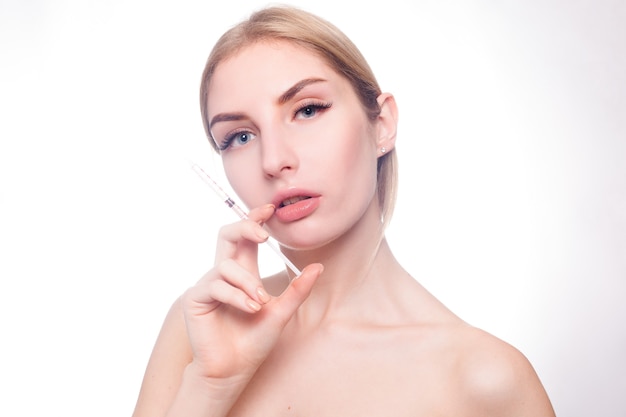 Concetto di bellezza, trucco e persone - La giovane donna attraente ottiene l'iniezione cosmetica, isolata sopra fondo bianco. Mani di medici che fanno un'iniezione in faccia. Trattamento di bellezza.