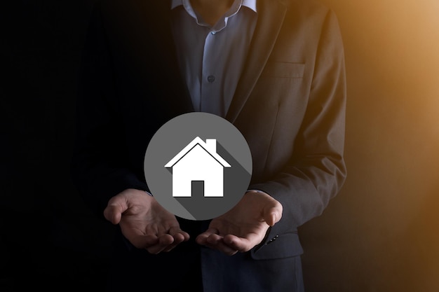 Concetto di bene immobile, uomo d'affari che tiene una casa icon.House on Hand.Property assicurazione e concetto di sicurezza. Gesto protettivo dell'uomo e simbolo delle icone house.flat con lunghe ombre.