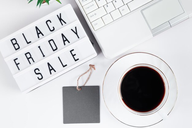 Concetto di Black Friday Laptop e tazza di caffè su sfondo bianco Vendita online