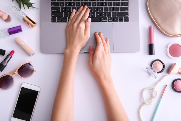 Concetto di blog di bellezza moderno computer portatile e cosmetici per le mani femminili vista dall'alto