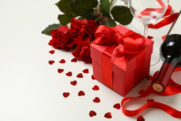 Concetto di buon San Valentino con vino, rose e confezione regalo su sfondo bianco