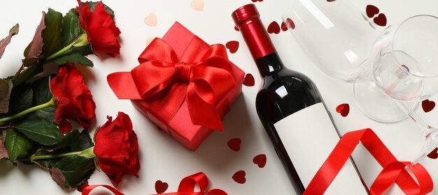 Concetto di buon San Valentino con vino, rose e confezione regalo su sfondo bianco