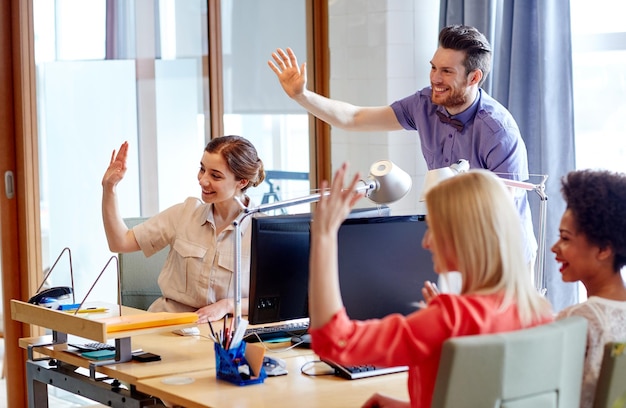 concetto di business, avvio e ufficio - felice team creativo agitando le mani in ufficio