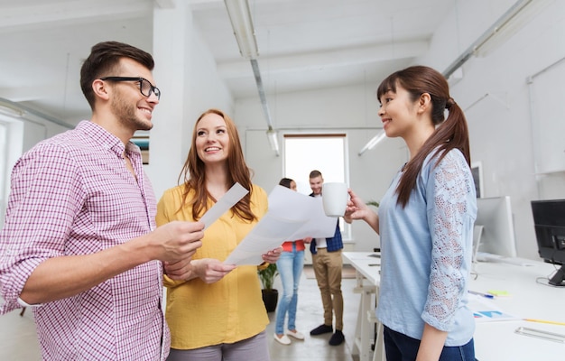 concetto di business, comunicazione, startup e persone - felice team creativo multirazziale o studenti in pausa caffè che parlano in ufficio