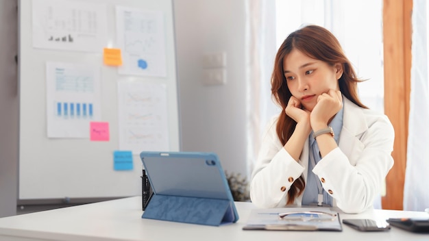 Concetto di business di successo Donna d'affari che riposa il mento a portata di mano per leggere i dati finanziari sul tablet